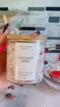 a hand holding a jar of coconut rose bath salts