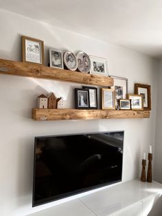 a flat screen tv sitting on top of a wooden shelf next to a white fireplace