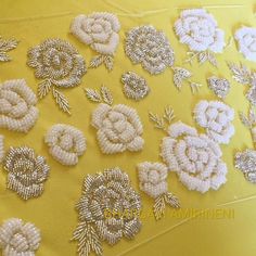 several different types of beaded flowers on a yellow surface with white trimmings