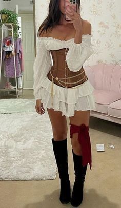 a woman in a corset taking a selfie with her cell phone while wearing knee high boots