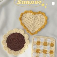 three crocheted heart coasters sitting next to each other on a white blanket