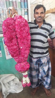 a man standing next to a bunch of pink flowers