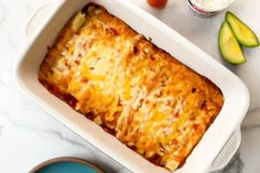 a casserole dish with cheese and vegetables next to an egg yogurt container