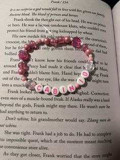 an open book with a pink beaded bracelet on it