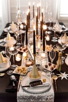 a table set with candles, plates and silverware for a festive dinner party