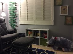 a living room with a chair, book shelf and elephant toy in front of the window