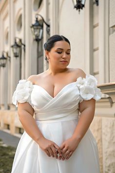 a woman in a white dress is standing outside