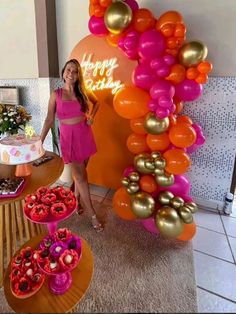 a woman standing in front of a table filled with cakes and desserts at a birthday party