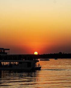 the sun is setting behind a boat on the water