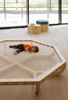 a young boy laying on top of a wooden floor next to a glass wall with large windows