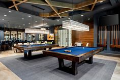 a billiard table and pool tables in a large room with wooden ceiling lights hanging from the ceiling