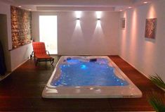 an indoor jacuzzi is lit up with blue lights in the living room area