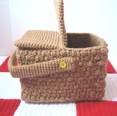 a crocheted basket sitting on top of a red and white blanket