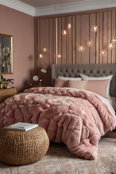 a bed with pink comforter and pillows in a bedroom