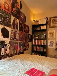 a bed with white sheets and lots of records on the wall next to bookshelves