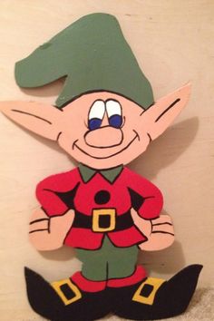 a wooden cutout of an elf sitting on top of a floor next to a wall