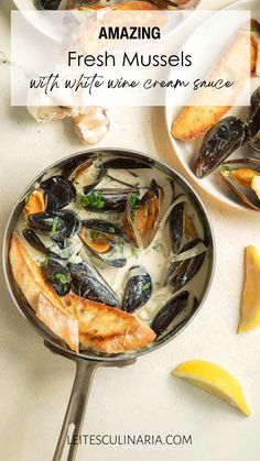 mussels with white wine and cream sauce in a pan next to lemon wedges