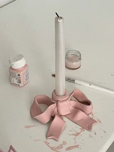 a white table topped with a pink candle and some crafting supplies next to it