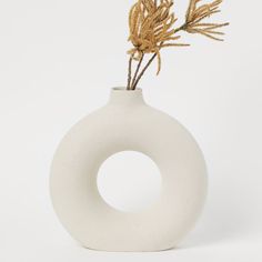 a white vase with some plants in it