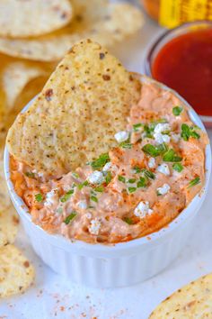 a white bowl filled with dip and tortilla chips on top of a table