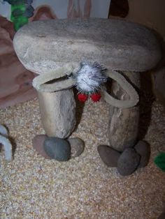 there is a small bird house made out of rocks and gravel with a stuffed animal on top