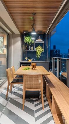 a table and chairs on a balcony with city lights in the backgroung