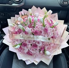 a bouquet of pink flowers sitting in the center of a car seat with a ribbon around it