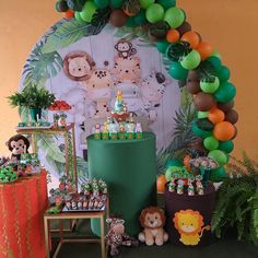 a jungle themed birthday party with balloons, decorations and animals on the wall behind it