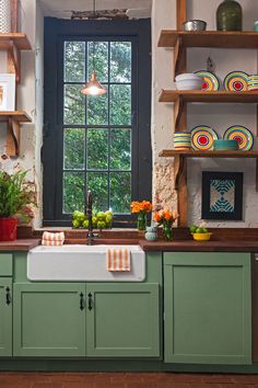 a kitchen filled with lots of green cupboards and counter top next to a window