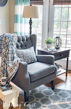 a living room with a chair, table and lamp in it's centerpiece