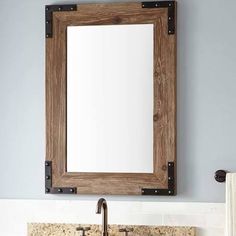 a bathroom sink with a wooden frame over it and a mirror on the wall above it