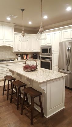 a kitchen with an island and stools next to the stove, refrigerator and oven