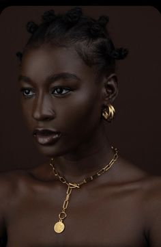 an african woman wearing a gold necklace and earrings