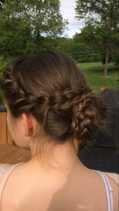 a woman with braids in her hair sitting on a bench looking at the grass