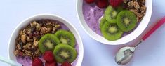 two bowls filled with fruit and granola on top of a white table next to a spoon