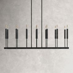 a black chandelier with candles hanging from it's sides on a gray wall