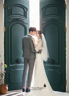 a bride and groom standing in front of an open green door at their wedding venue