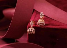 two pairs of gold and diamond earrings sitting on top of a red velvet cloth covered box