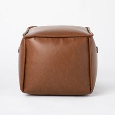 a brown leather bag sitting on top of a white surface