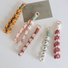 four bracelets with flowers on them sitting next to a card and keychain