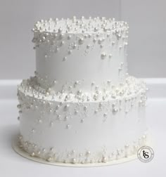 a three tiered white wedding cake with pearls