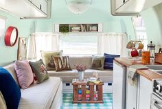 a kitchen and living room in an airstream with blue walls, checkered flooring and white trim