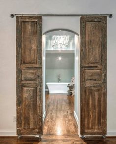 an open door leading to a bathroom with a chandelier hanging from the ceiling