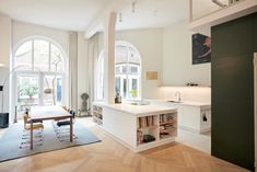 an open kitchen and living room with large arched windows in the back ground floor area