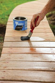 a man is painting a wooden bench with a paintbrush and a can of wood