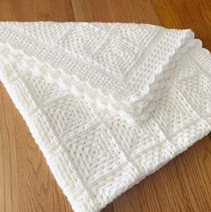 a white knitted blanket laying on top of a wooden floor