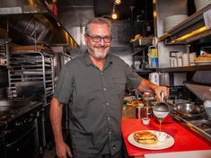 a man standing in a kitchen pouring something into a bowl on top of a plate