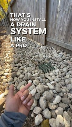 a hand pointing at rocks on the ground with text that reads, that's how you install a drain system like a pro