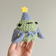 a crocheted frog with a party hat on it's head is held up in the air