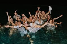 a group of people are in the water posing for a photo with their hands up